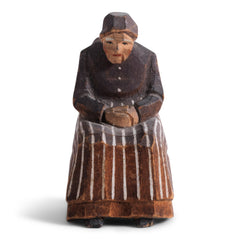 A miniature naive carved wooden figure of a peasant women seated on an Alpine chair, with its original staining and paint - mid century, Bavarian.