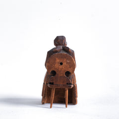 A miniature naive carved wooden figure of a peasant women seated on an Alpine chair, with its original staining and paint - mid century, Bavarian.