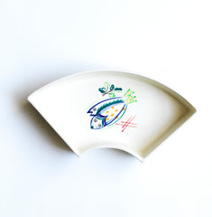 Part of a mid century vintage Poole Pottery seafood hors d'oeuvre set consisting of five ceramic dishes that fit snugly into a circular wooden tray. Each crescent shaped dish is decorated with a hand painted pattern of a shrimp, a flatfish (as shown here), a crab and a scallop - designed by Truda Carter and hand painted on Poole Pottery's alpine white glaze. Each piece is stamped to its underside "Handmade Hand Decorated Poole England", along with the paintress's mark.