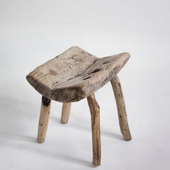 An antique primitive wooden stick stool, the top crafted from a single section of trunk.