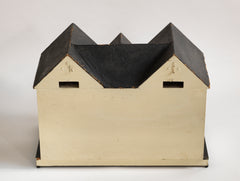 A Tudor style doll's house in the 1930s Mock-Tudor vernacular with twin jettied oriel windows and leaded glass style metal window frames.