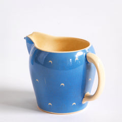 The milk jug  in a complete 1930s Art Deco Susie Cooper Blue Crescent Kestrel coffee set decorated with small scarffito crescents. It includes a coffee pot, milk jug, sugar bowl, and six coffee cans and saucers.