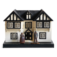 A Tudor style doll's house in the 1930s Mock-Tudor vernacular with twin jettied oriel windows and leaded glass style metal window frames.