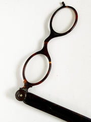 An Edwardian faux tortoiseshell lorgnette - an elegant  pair of fine oval spectacles attached to a long arm in  mock tortoiseshell.