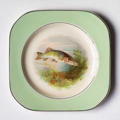 A fish pattern plate, and part of a glorious 1930s fish dinner service, complete with a large platter for serving a whole fish.  Each piece is embellished with a fresh water fish, such as pike, perch and trout, and contained within a mint-green border. Each item is stamped "Woods Ivory Ware England" to its underside.