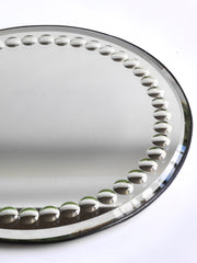 A large and very striking late 19th century tabletop circular mirror with a border of convex fish-eye inclusions, a bevelled edge and a fine metal trim. It has a cream painted back and stands of on three bun feet. 
