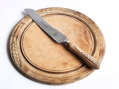 An antique bread board with matching bread knife, each carved with stylised wheat-sheaf motifs. The bread board is of sycamore, richly carved, and sits on a slightly raised foot. The knife has a wheat sheaf patterned handle with "Bread Knife" engraved on its blade; which is fitted to a stainless steel blade, marked "Butler, Sheffield, England". The knife and board have been much loved, and have a wonderful polished patina.