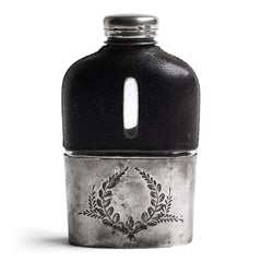 A quality Edwardian silver plated, glass and black leather hip flask with a screw-cap top, and beautiful leaf decoration etched into the silver plate. The clear glass body is half covered with leather, the lower half has a detachable silver plated cover that also acts as a cup.