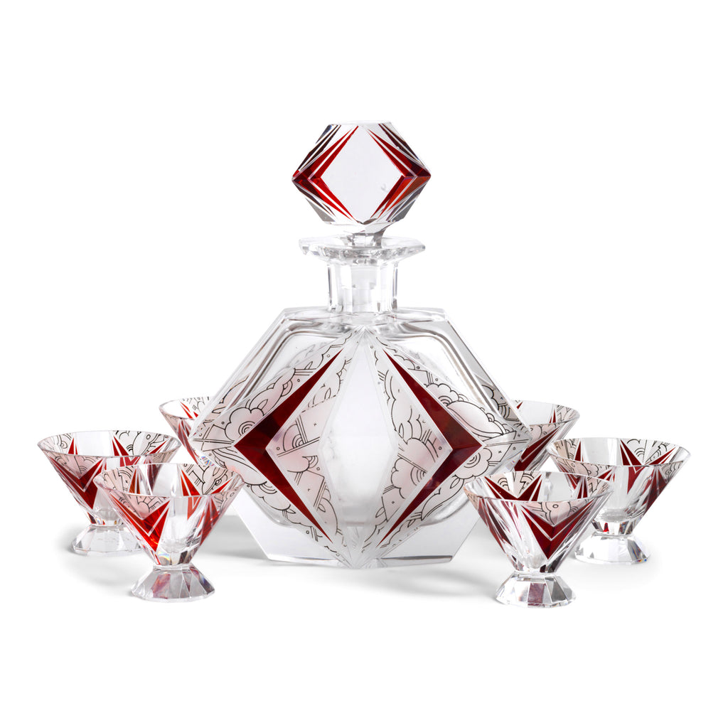 A stunning and rare Art Deco etched black and ruby glass decanter set designed by Karl Palda c.1930. The set comprises of a decanter with stopper and six conical shaped facet cut glass cocktail glasses, each with a flaring foot. Each piece is decorated with Art Deco geometric florals and red chevrons.