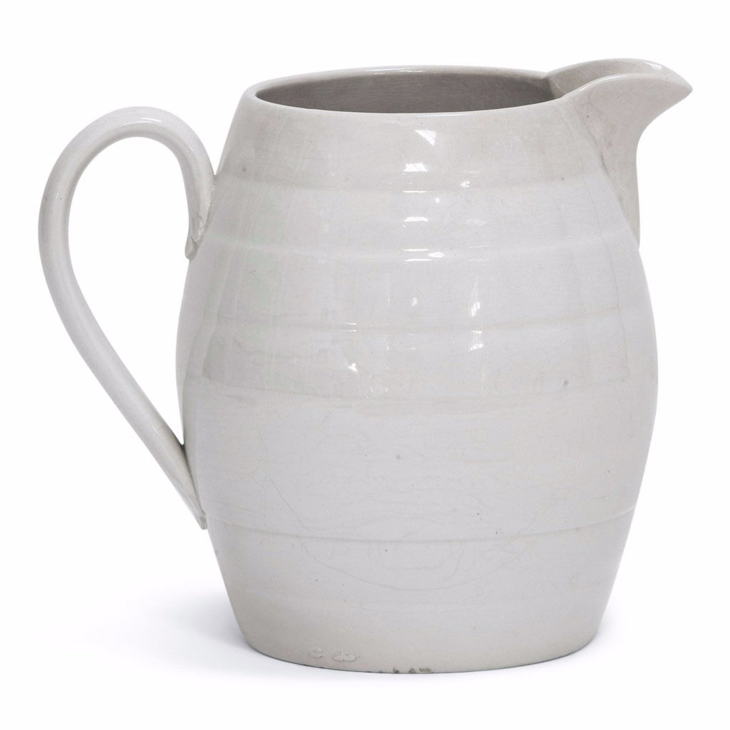 A 1920s barrel-shaped creamware water jug. Plain, unadorned water jugs with clean-lines and simple forms were part of the everyday 19th and early 20th century kitchen. Their purity and functionality is as appealing today as it was then; and when used for either water, milk or flowers, or simply amassed as a decorative collection, they make an arresting addition to the modern home.