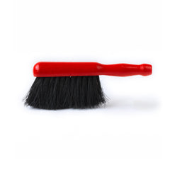 A dustpan brush with natural coconut bristles and a red painted wooden handle.