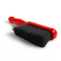 A dustpan brush with natural bristles and a red painted wooden handle.