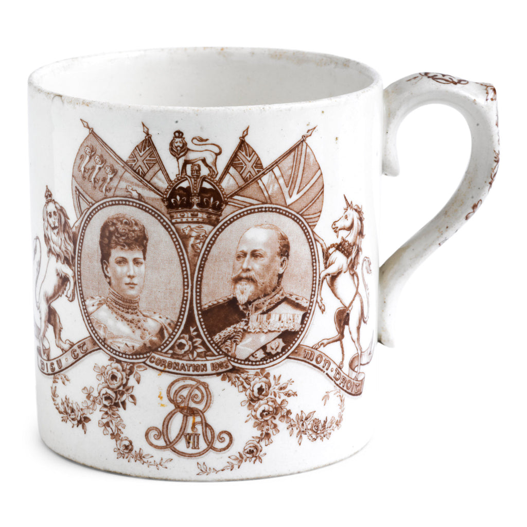 An Edwardian Edward VII coronation mug with tin white glaze by Royal Dolton, made to commemorate his coronation in 1902. "Long life and happiness King Edward VII and his beloved consort Queen Alexandra crowned June 26th 1902" amid a crown of oak and laurel leaves illustrates the rear; and a portrait of Edward VII and Queen Mary and "E R" decorates the main body of the mug - along with flags, a lion, a unicorn and swags of roses.