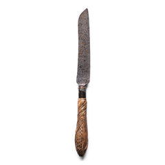 A Victorian bread knife with carved sycamore handle, and carbon steel engraved blade by "Taylor Whitners Sheffield". The handle has a spiralled wheat sheaf and "Bread" carved decoration. 