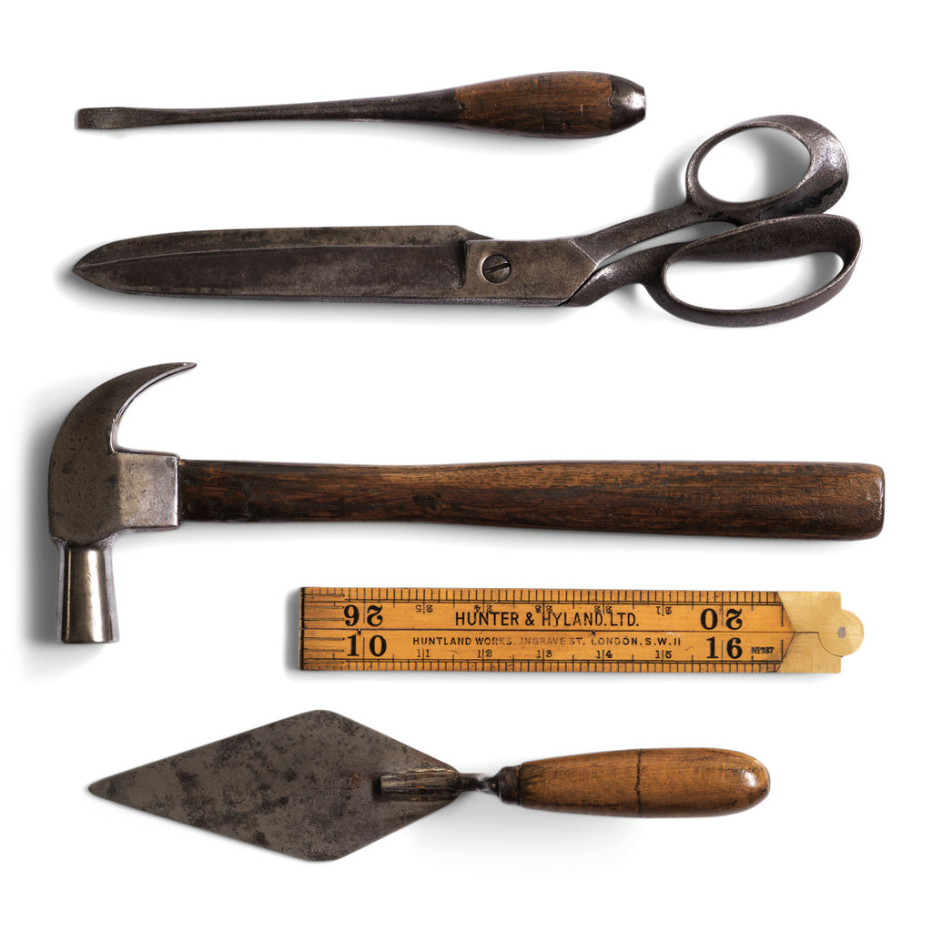 A collection of handmade vintage and antique tools, including a screw driver, tailors shears, claw hammer, carpenters rule and a trowel.