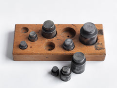 A complete set of 1920s post office scales' weights in their original wooden stand, calibrated in grammes and kilos. Once used for weighing small parcels, they could now be used in the kitchen in combination with a traditional set of scales for weighing out ingredients. Total weight of weights 2.55kg