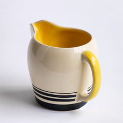 A Susie Cooper 1930s kestrel shape milk jug and sugar bowl in Cooper's classic art deco Yellow Tango pattern. Each piece is stamped to the underside "Susie Cooper Production Crown Works Burslem" and bears the Susie Cooper leaping deer trademark. 